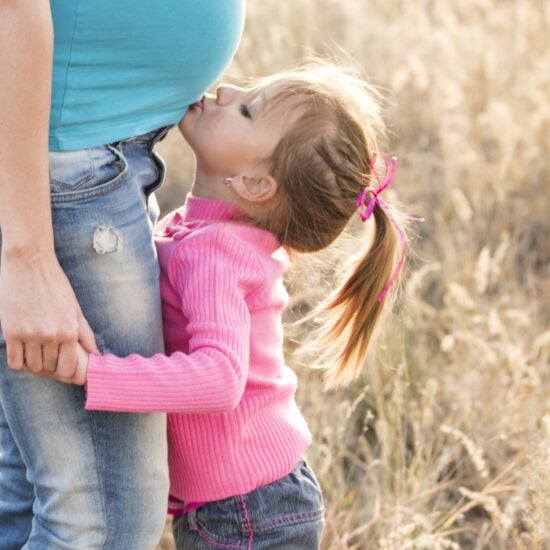 Child kissing pregnant belly